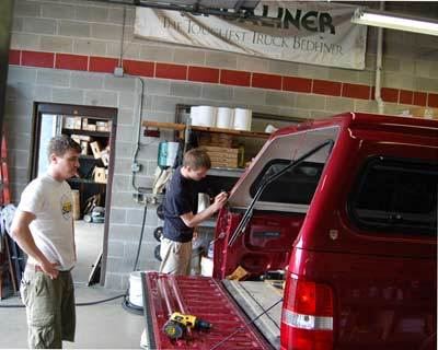 Installation of a truck cap on a red truck with the owner watching the work